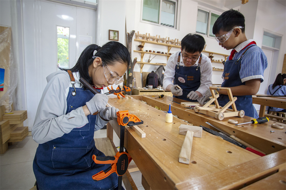 6月12日，河北省邯郸市复兴区实验小学木工教室里，老师（中间）在指导学生“‌榫头卯眼”精准拼接‌。聂长青摄