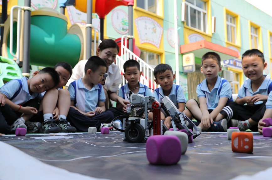 6月13日，孩子们在体验机器人踢足球。田博摄