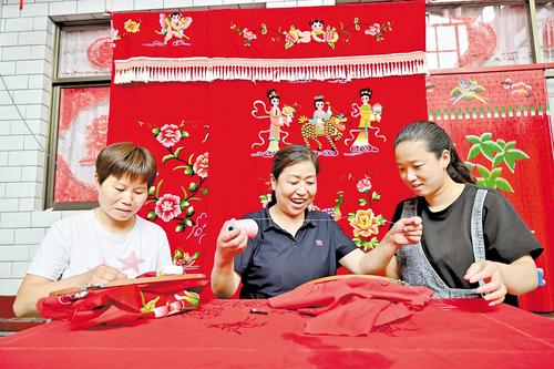 6月20日,賀彥霞(中)帶動周邊村庄婦女一起刺繡,共同致富。本報記者 田明攝
