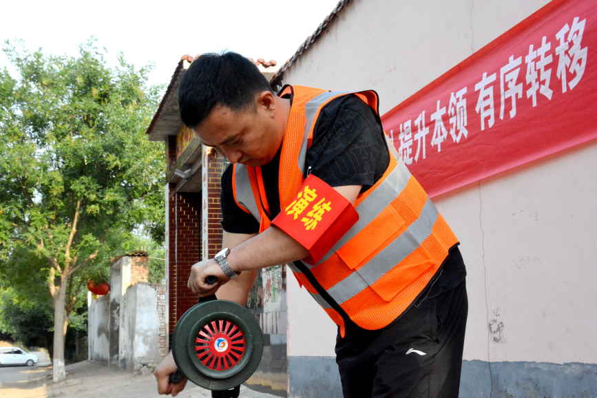 工作人员在通过手摇报警器的方式向村民发出转移通知。彭锦帅摄