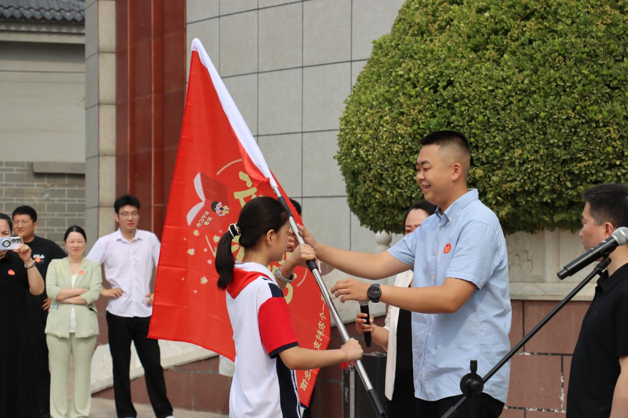 活动现场，门泽朋将旗帜传递到新一代讲解员手中。安平县委宣传部供图