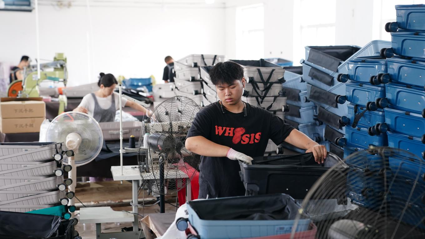 7月4日，工人在白溝新城鵬杰皮具有限公司生產車間忙生產、趕訂單。孫珞瑜攝
