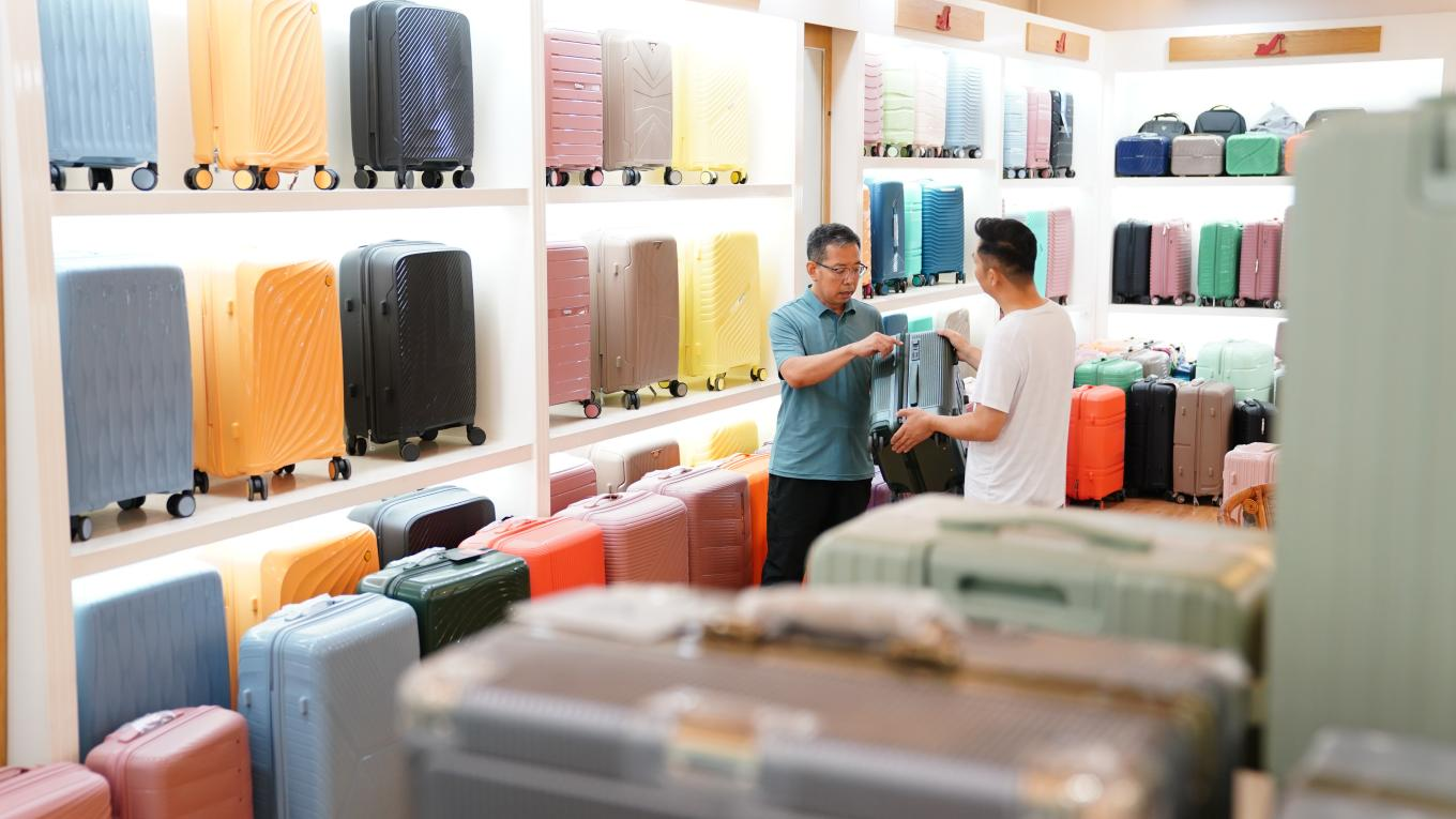 7月4日，白溝新城鵬杰皮具箱包展廳，總經理王金龍向客戶介紹箱包產品。孫珞瑜攝