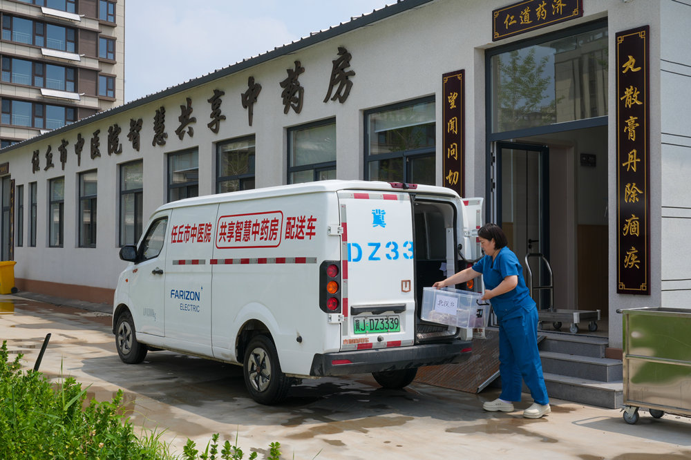 工作人员将熬制好的中药装车运走。韩慧峰摄