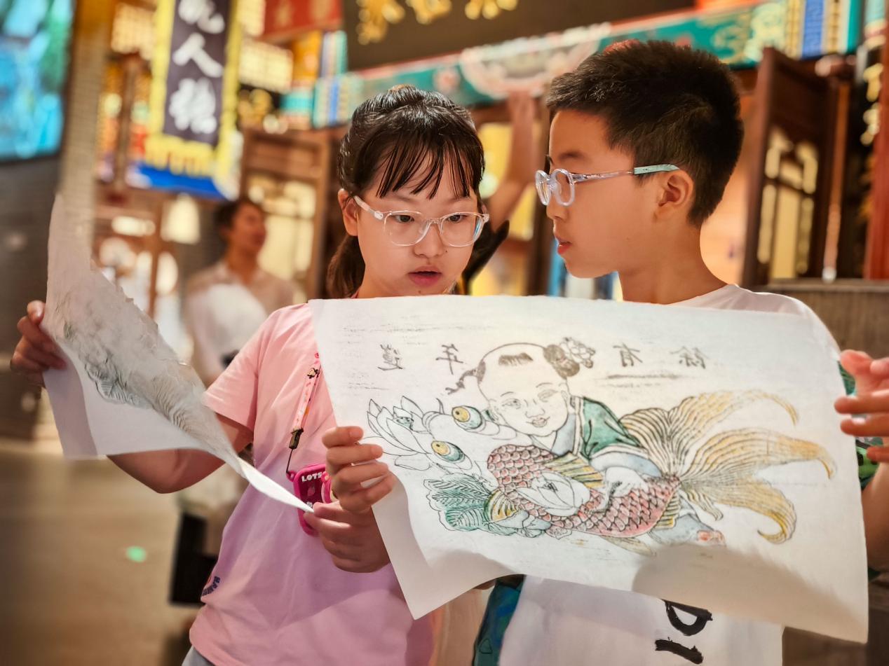 两个小学生切磋各自印制的年画作品。 傅新春摄