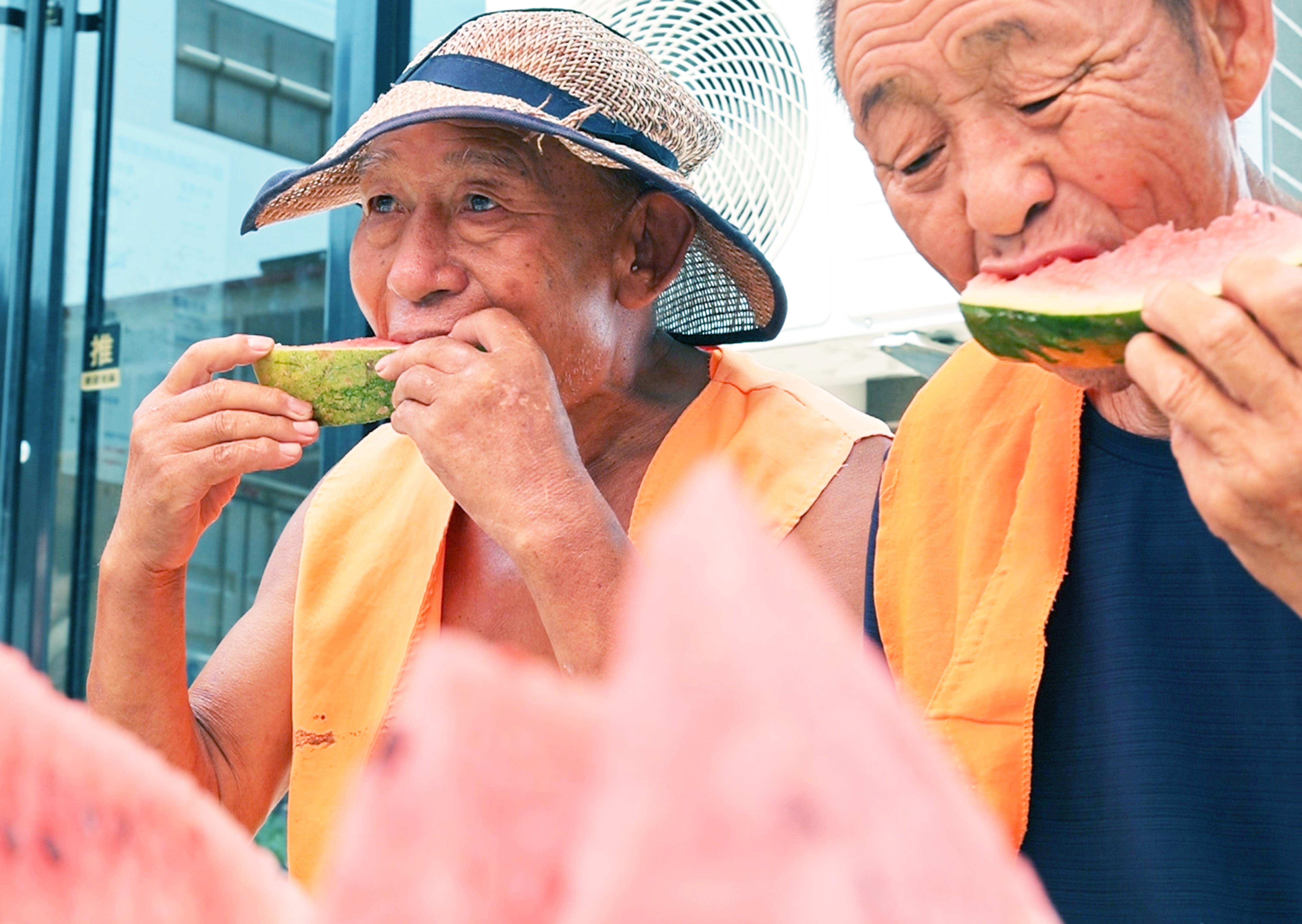 环卫工人正在吃爱心商铺提供的西瓜。滕桂芹摄