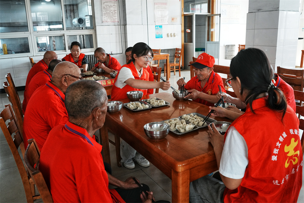 7月18日，在迁安市第三福利院，沙河驿镇志愿者正在与老人们共享“福”饺。张泽慧摄