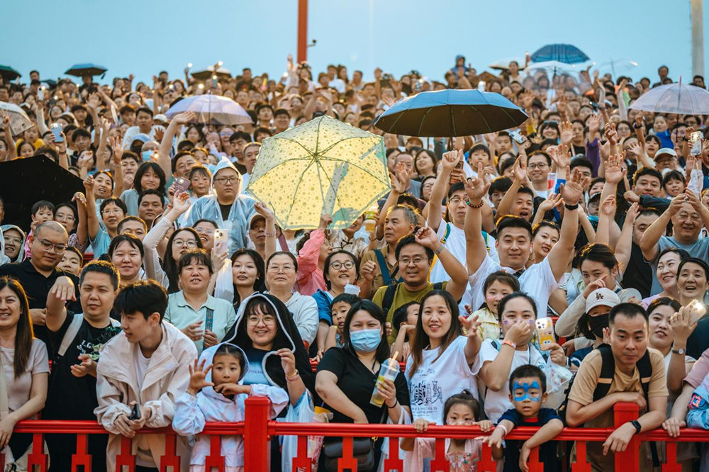 冒雨来到河头老街的游客们正聚精会神地观看着实景演出。魏永摄