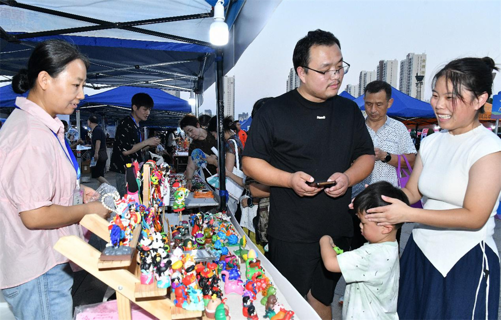 8月11日，在沧州狮城公园主会场，市民在非遗展示区挑选面塑作品。苑立伟摄