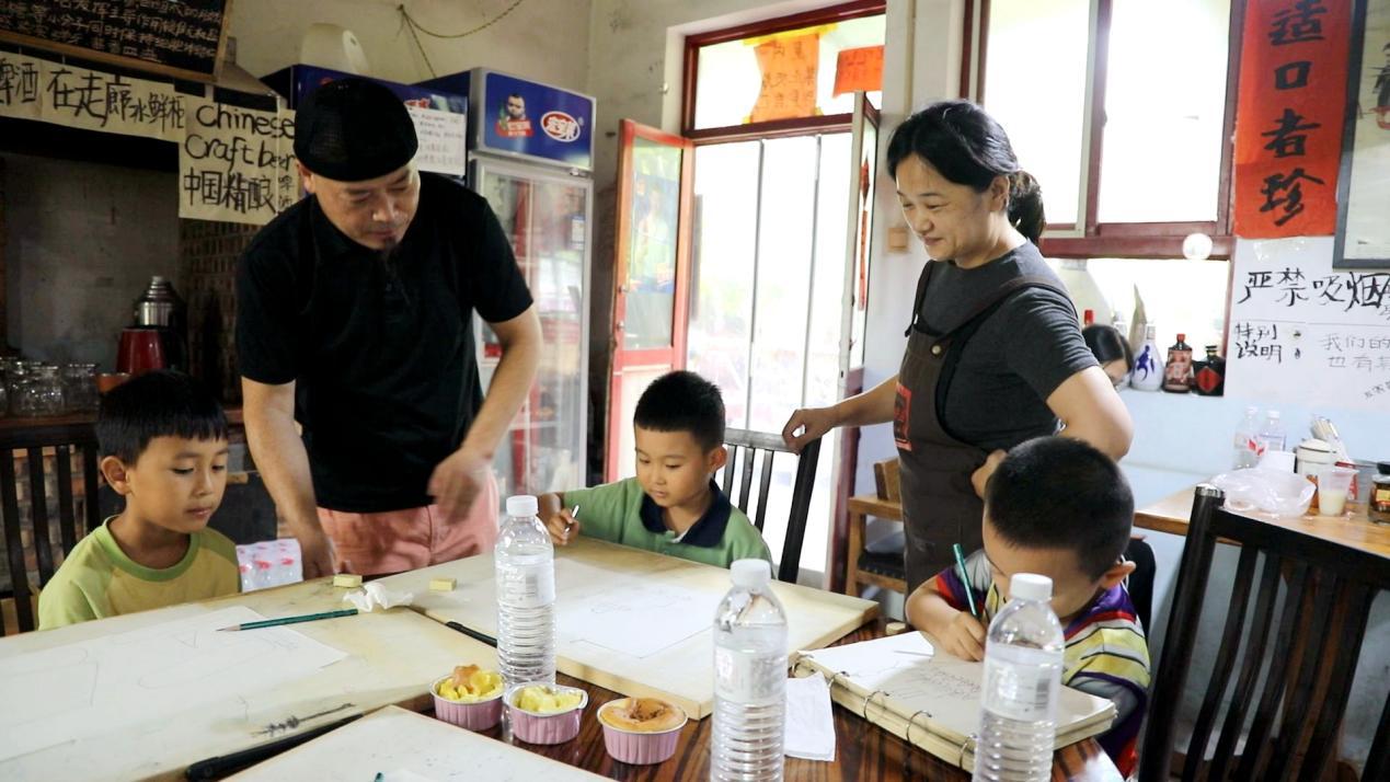 8月12日，在易县安格庄村公益美育课堂上，赵忠、史丽杰夫妇在欣赏孩子们的画作。付鑫源摄