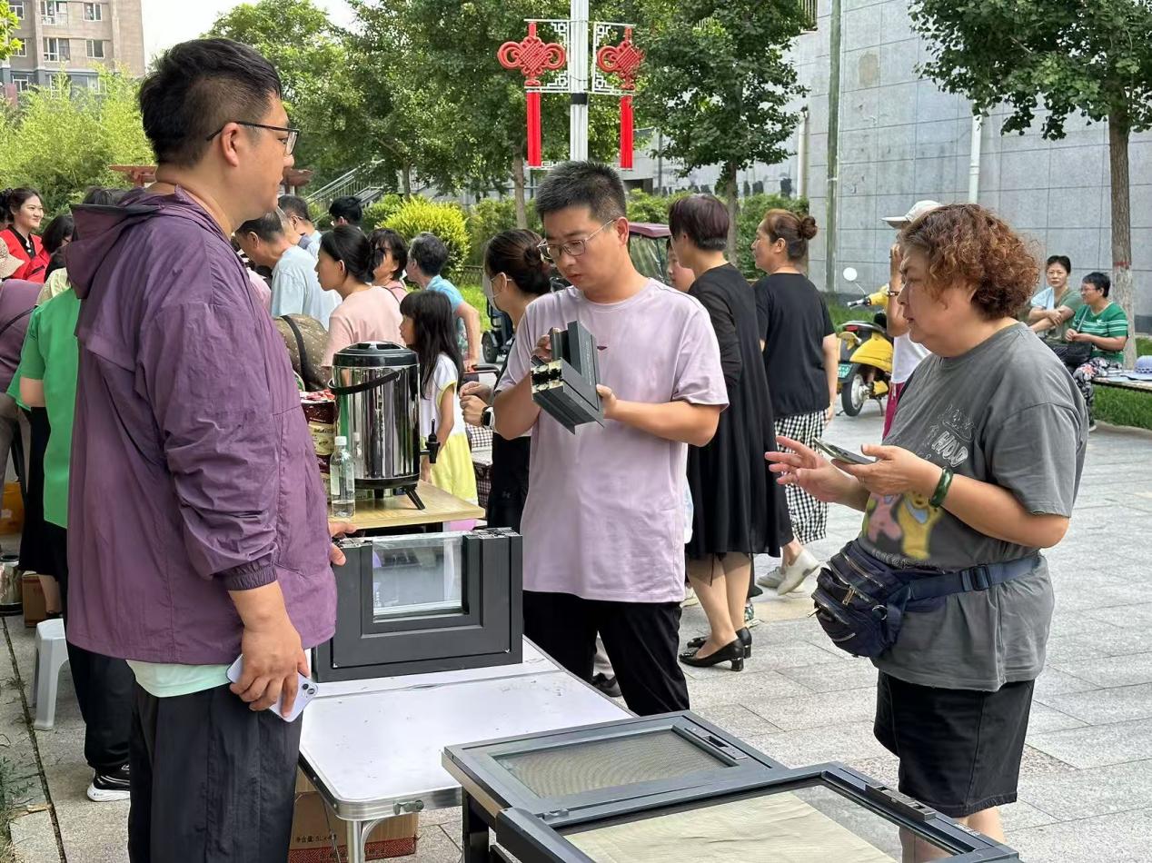 工作人员为居民介绍免费更换窗户密封条服务内容。黄杉杉摄
