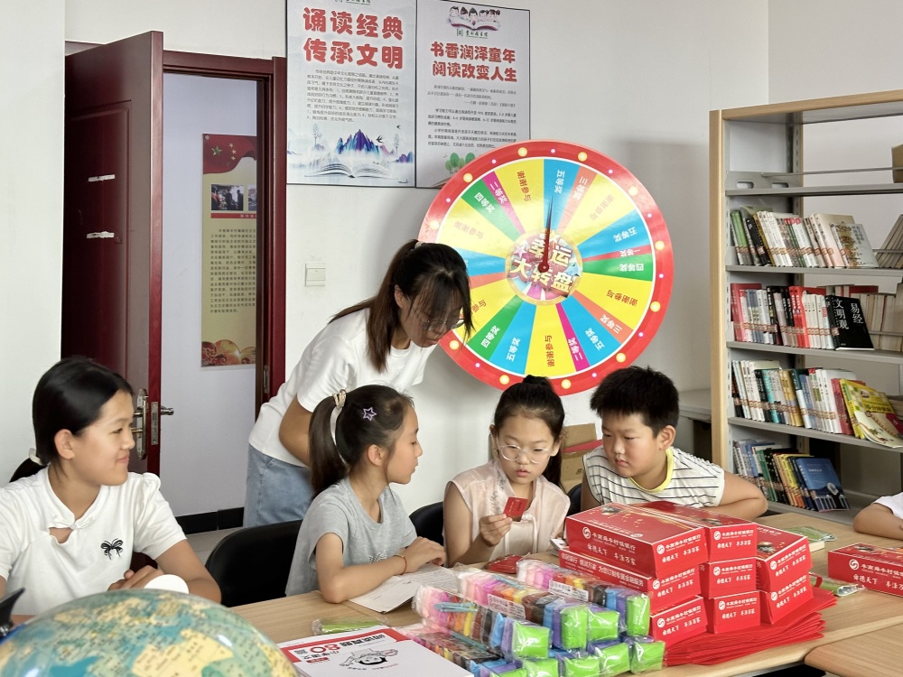 在图书馆内,返乡大学生与孩子们一起进行诵读活动。杨雨馨摄