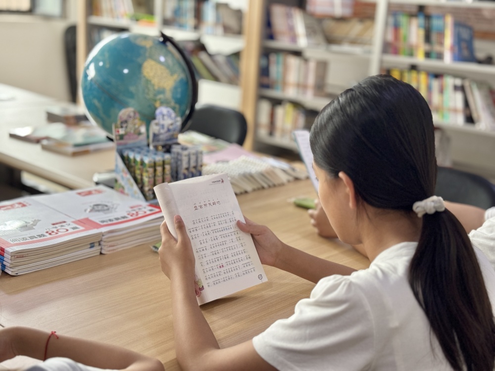 在图书馆内，返乡大学生与孩子们一起进行诵读活动。杨雨馨摄
