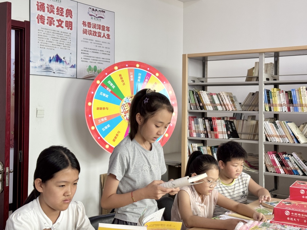 在图书馆内，返乡大学生与孩子们一起进行诵读活动。杨雨馨摄