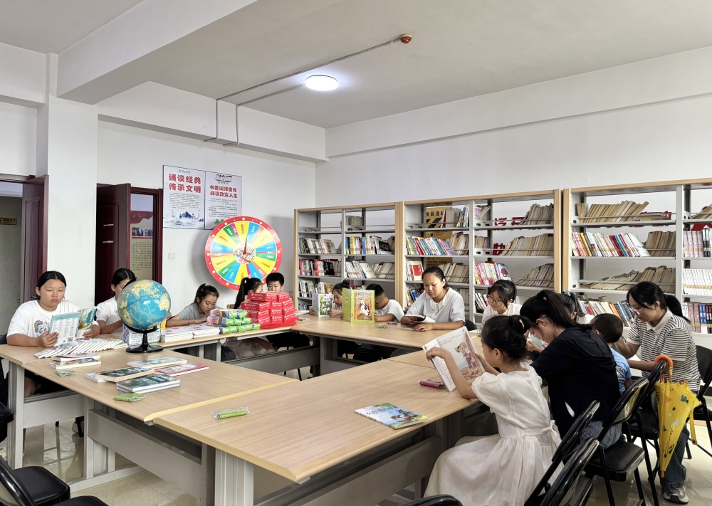 在图书馆内，返乡大学生与孩子们一起进行诵读活动。杨雨馨摄