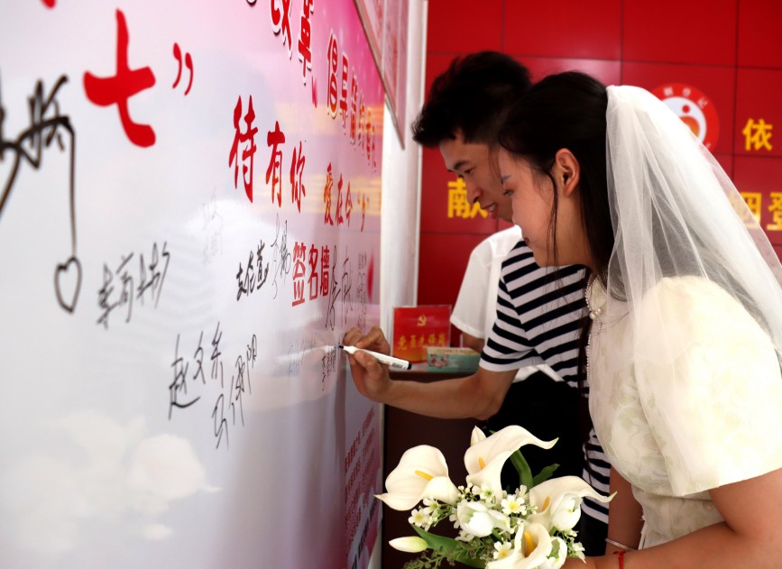 新人在“文明婚恋承诺”签名墙上签字。李谦摄