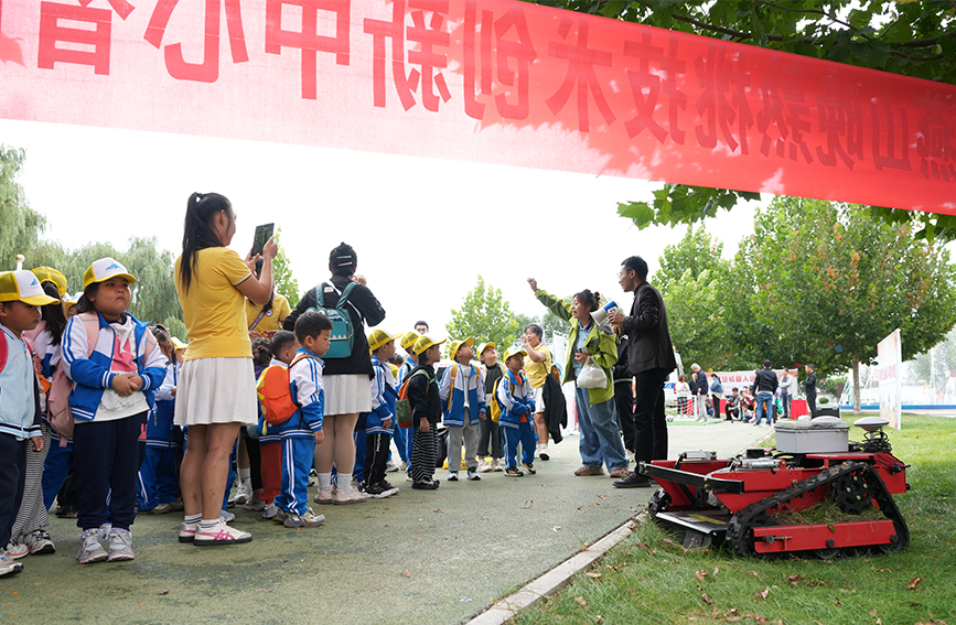 工作人员正在向参加研学的同学们讲解农业除草机器人。张泽慧摄