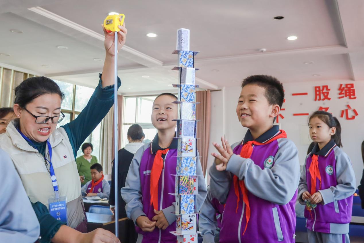 评委老师正在测量学生搭建的纸牌高塔高度。郭春朝摄