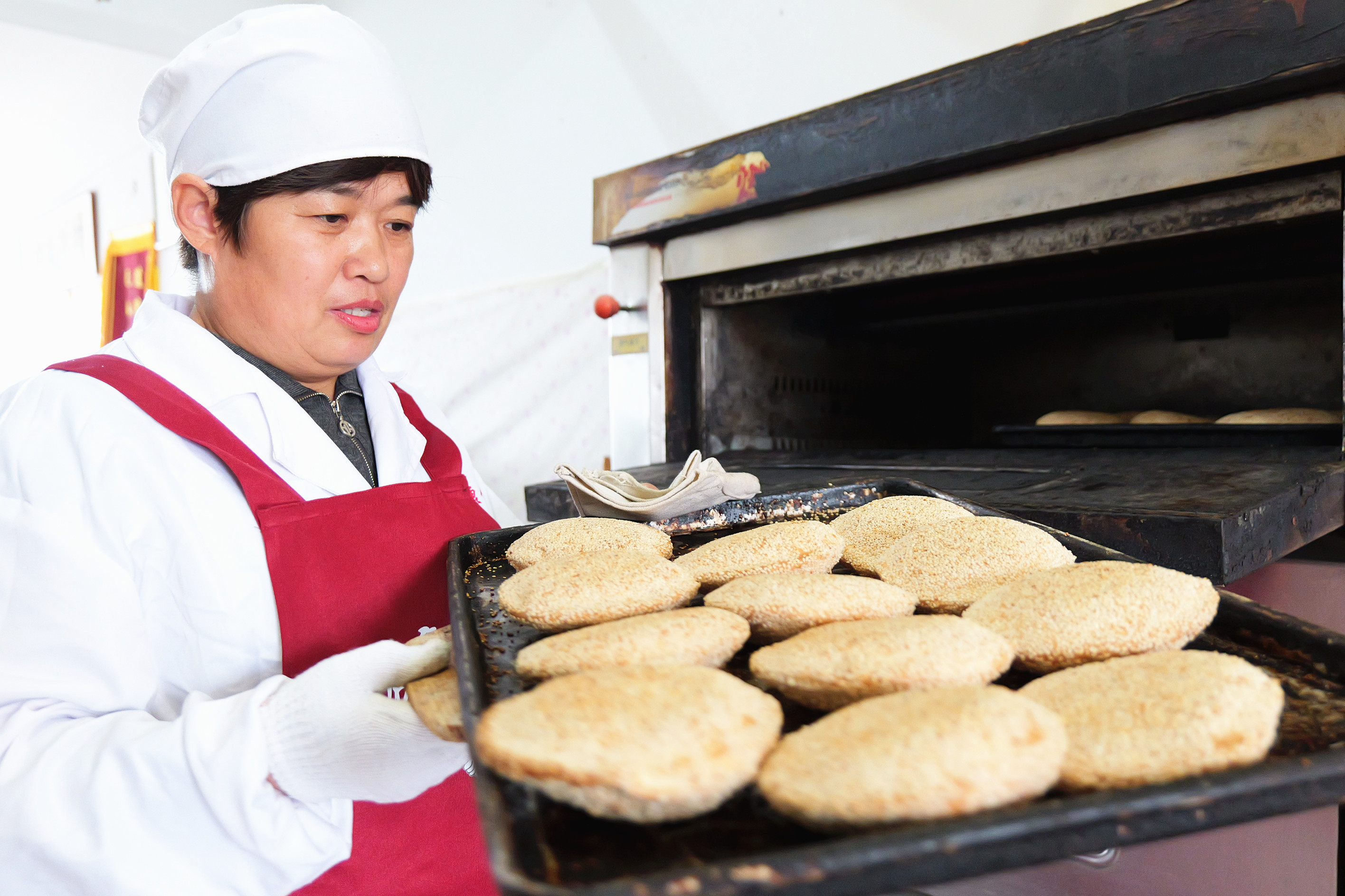 10月17日，范秀娥从烤箱中取出烤制完成的烧饼。王洪胜摄 