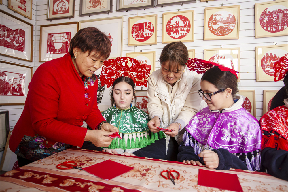 10月22日，河北省邯郸市复兴区户村镇户村村，冯石萍为留学生传授剪纸技法。聂长青摄