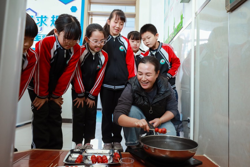 肃宁县河北留善寺镇希望小学学生在观察老师制作糖葫芦。郭春朝摄