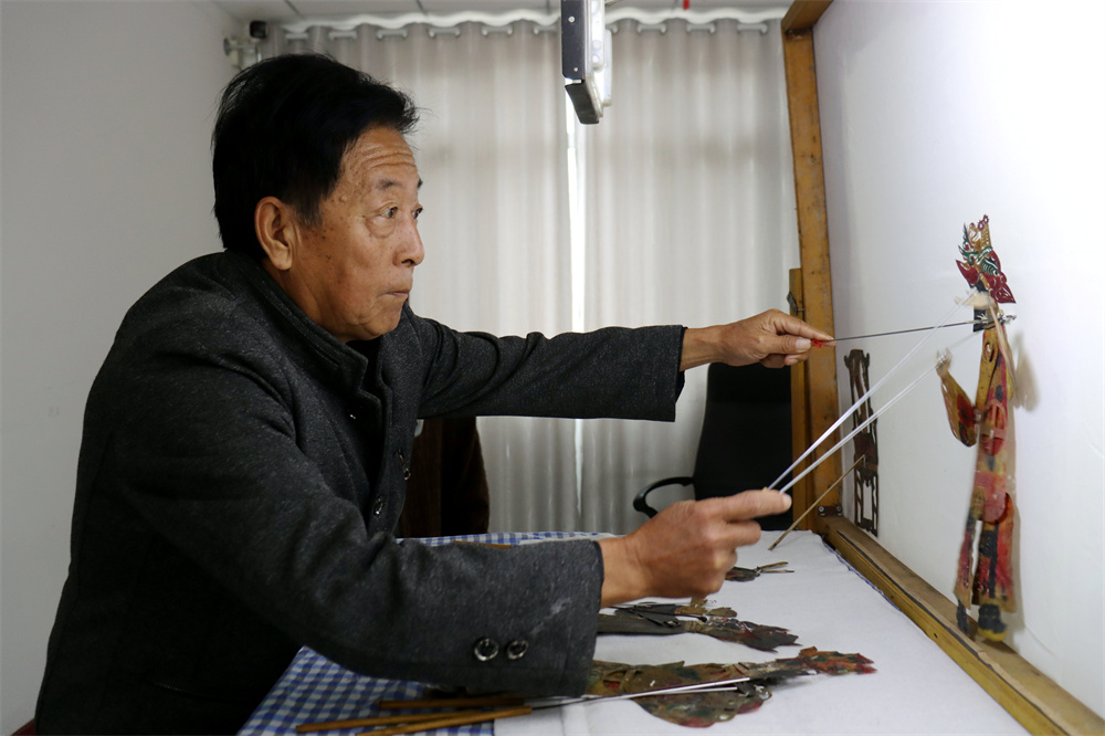 张维宗在为老人们表演皮影戏。李谦摄