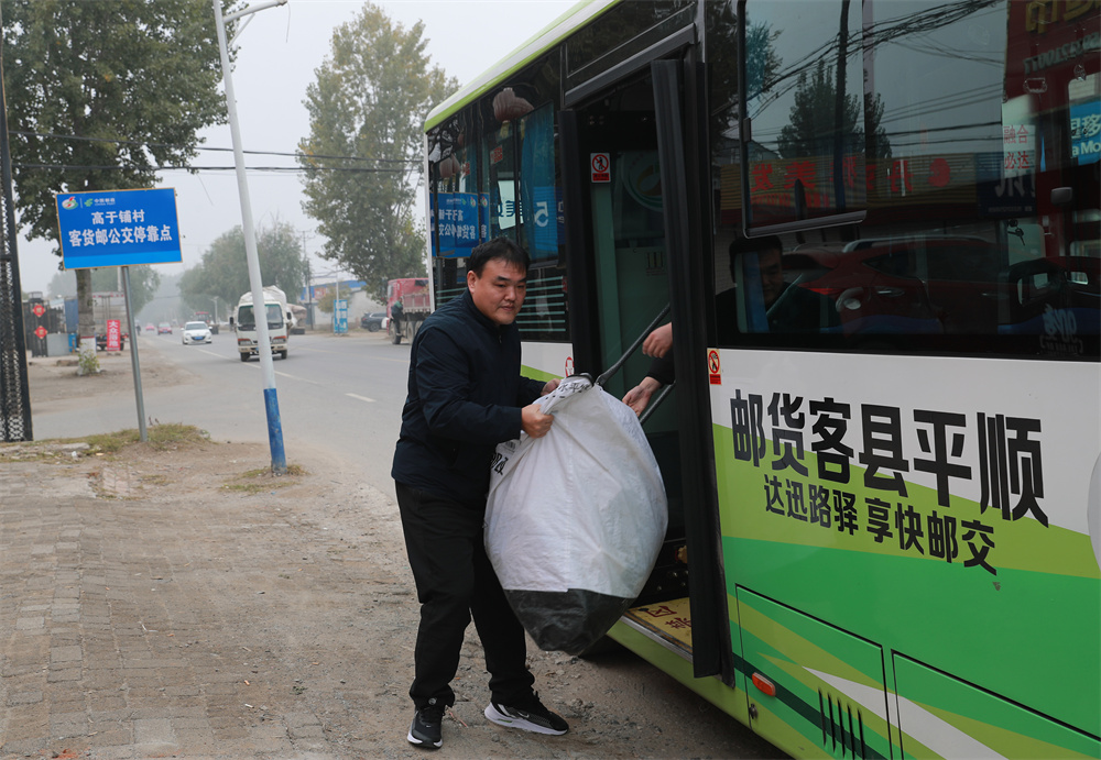 客货邮一体公交车向沿途村级网点派送包裹。赵端摄