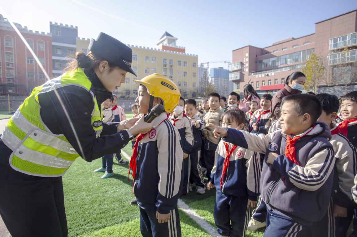 11月26日，河北省邯郸市复兴区实验小学操场，交警指导孩子们正确佩戴头盔。聂长青摄