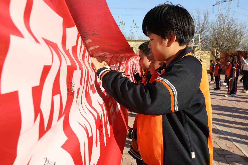 11月20日，小学生在责任与担当倡议条幅上签名。刘金忠摄