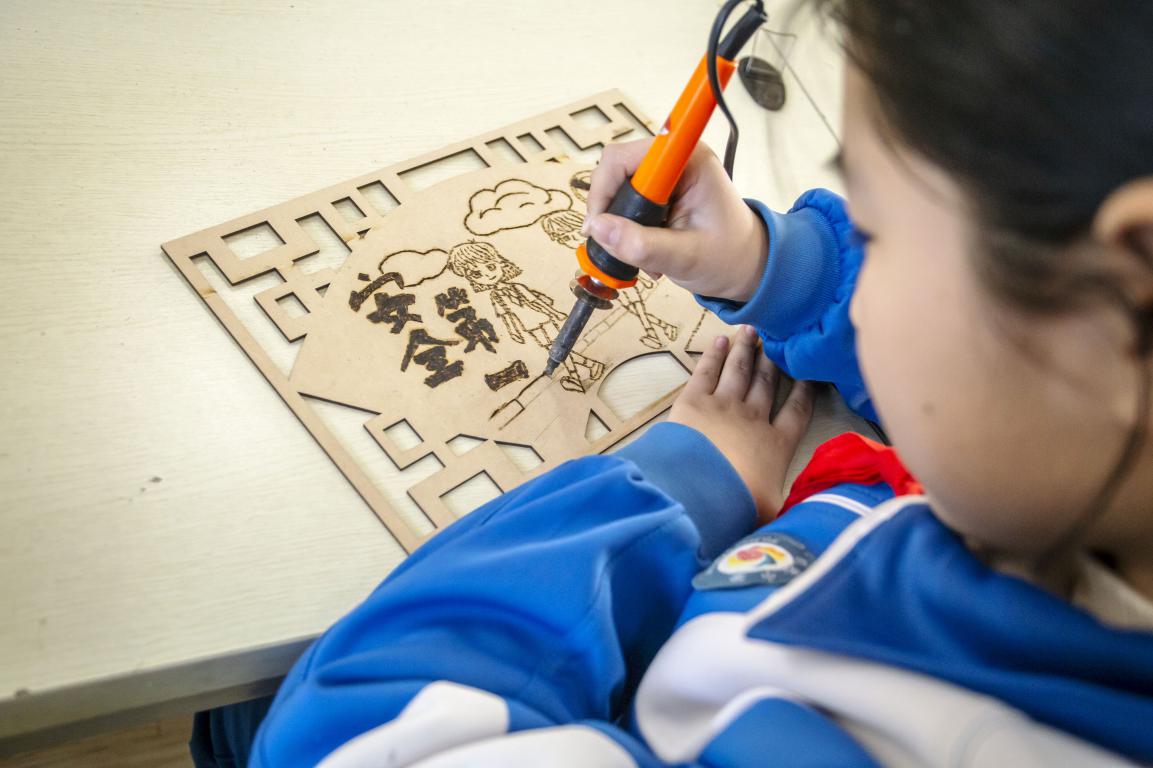 11月27日,河北省邯郸市复兴区时光小学的孩子们在老师指导下,通过剪纸、衍纸、烙画技艺等学习交通安全知识。聂长青摄
