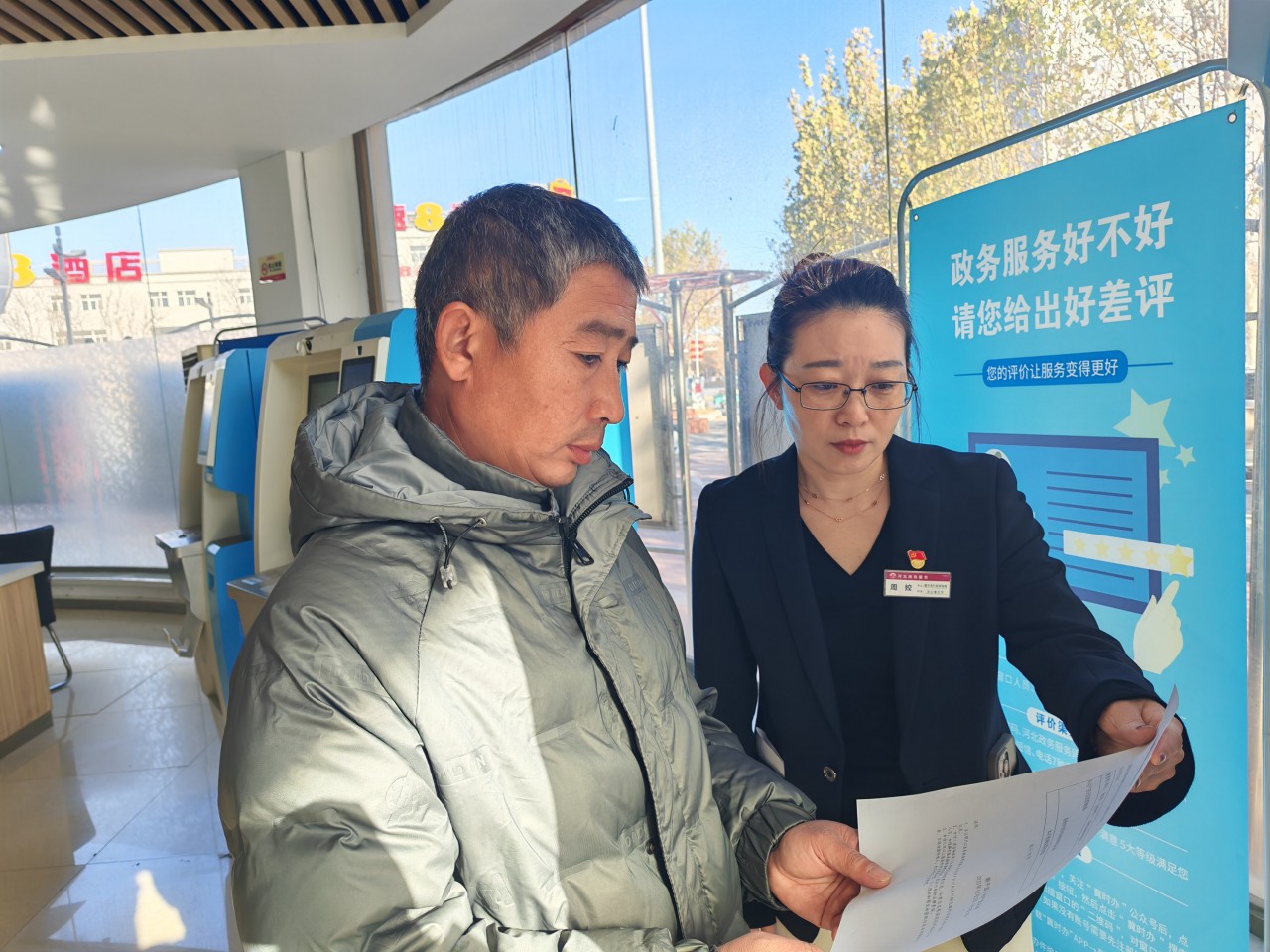 政务服务大厅内,申请人在工作人员帮助下打印申请资料。赵端摄