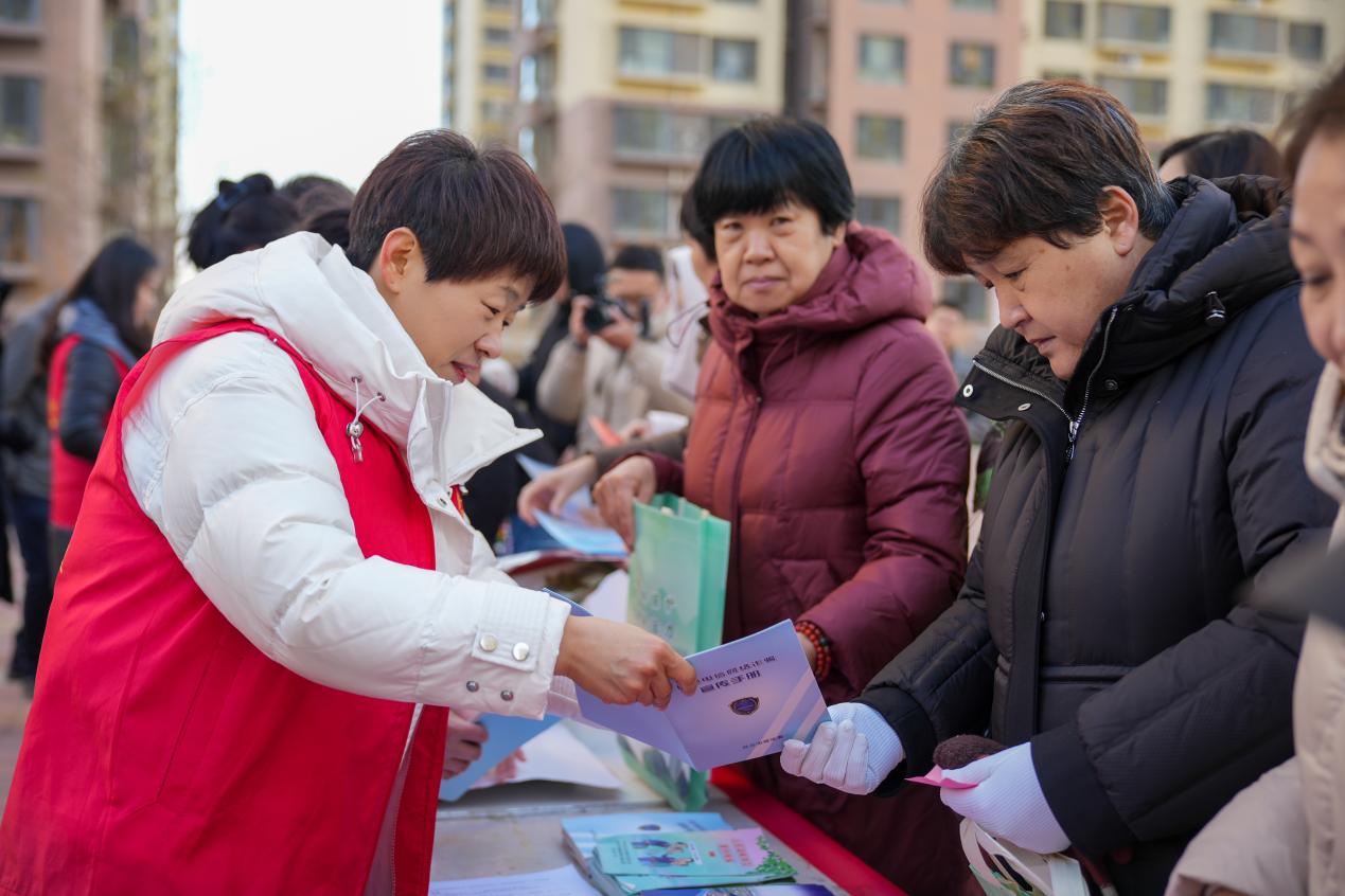 社区志愿者为居民发放普法宣传手册。韩慧峰摄