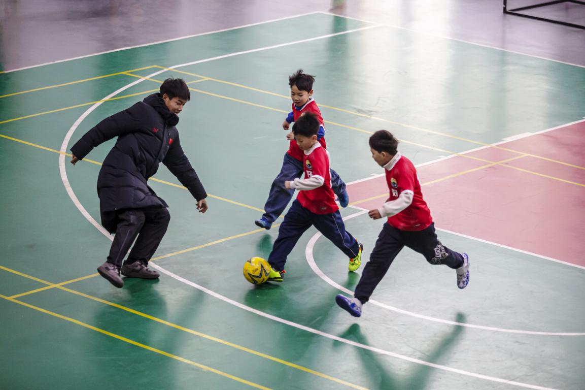 12月19日,河北省邯郸市复兴区美好小学校园内,孩子们在“河北五超”队员的指导下开展足球基本功训练。聂长青摄