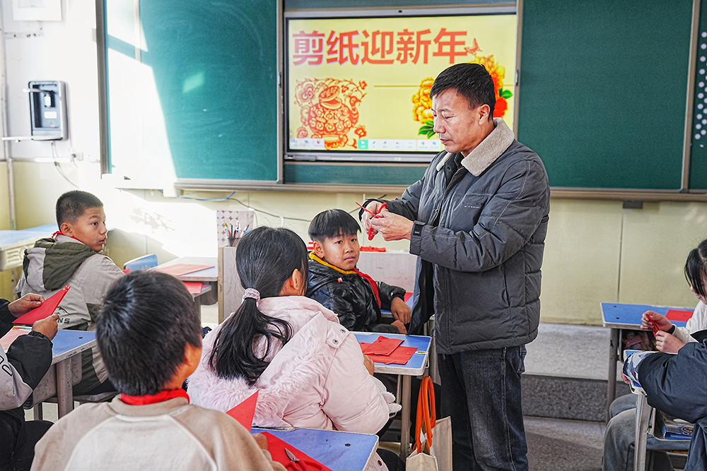 12月25日,非物质文化遗产代表性传承人正在一对一指导学生剪纸。张泽慧摄