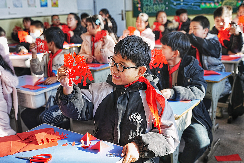 12月25日,学生们正在欣赏自己亲手剪出来的剪纸作品。张泽慧摄