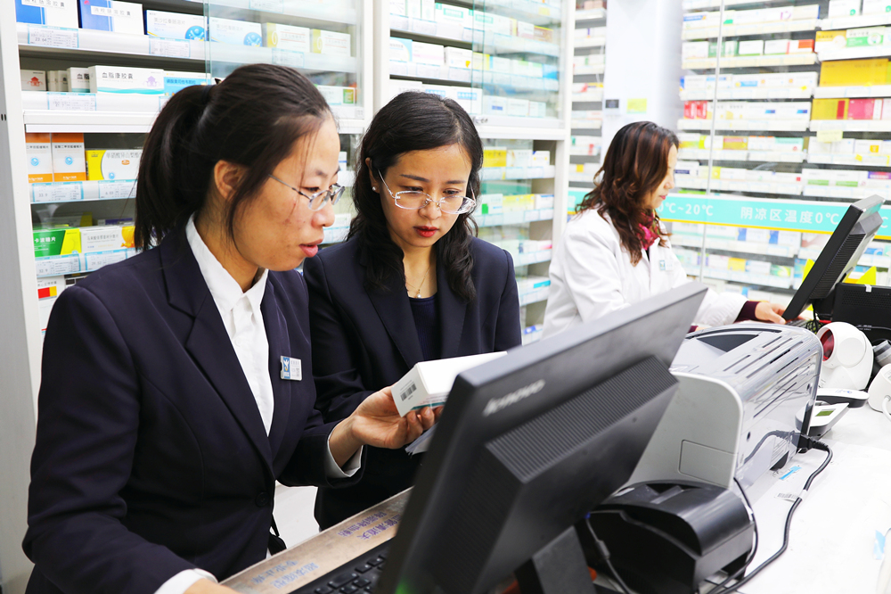 张家口市桥东区医疗保障局工作人员（中）在了解集采药品销售情况。岑屹摄