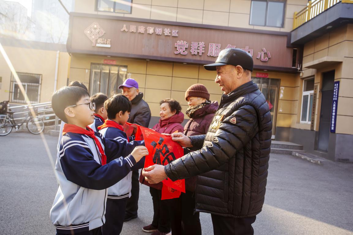 孩子们将写好的春联赠送给社区老党员。聂长青摄