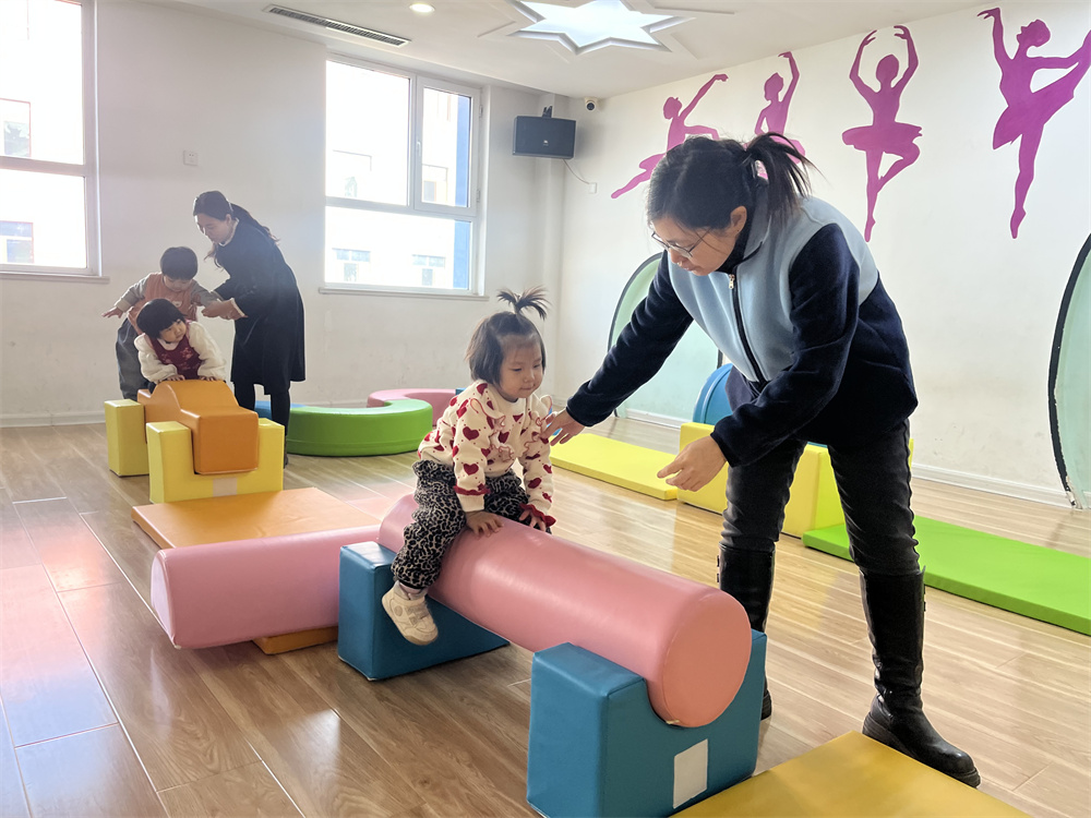幼兒園老師輔導孩子利用感統器材訓練。郭強攝