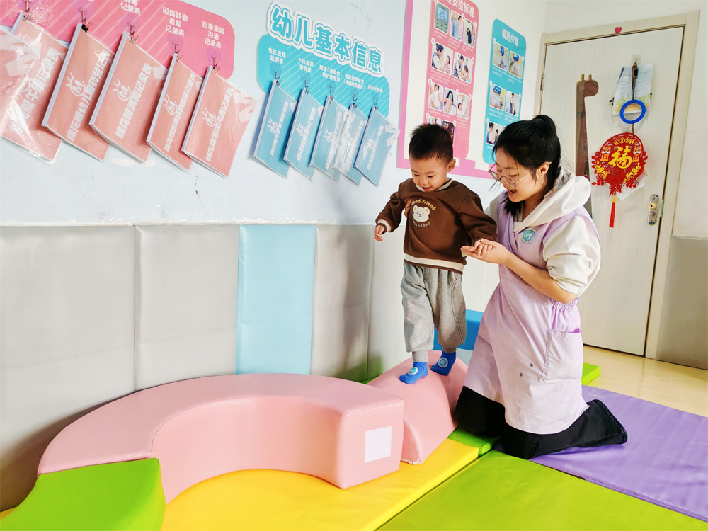 幼兒園老師輔導孩子利用感統器材訓練。郭強攝