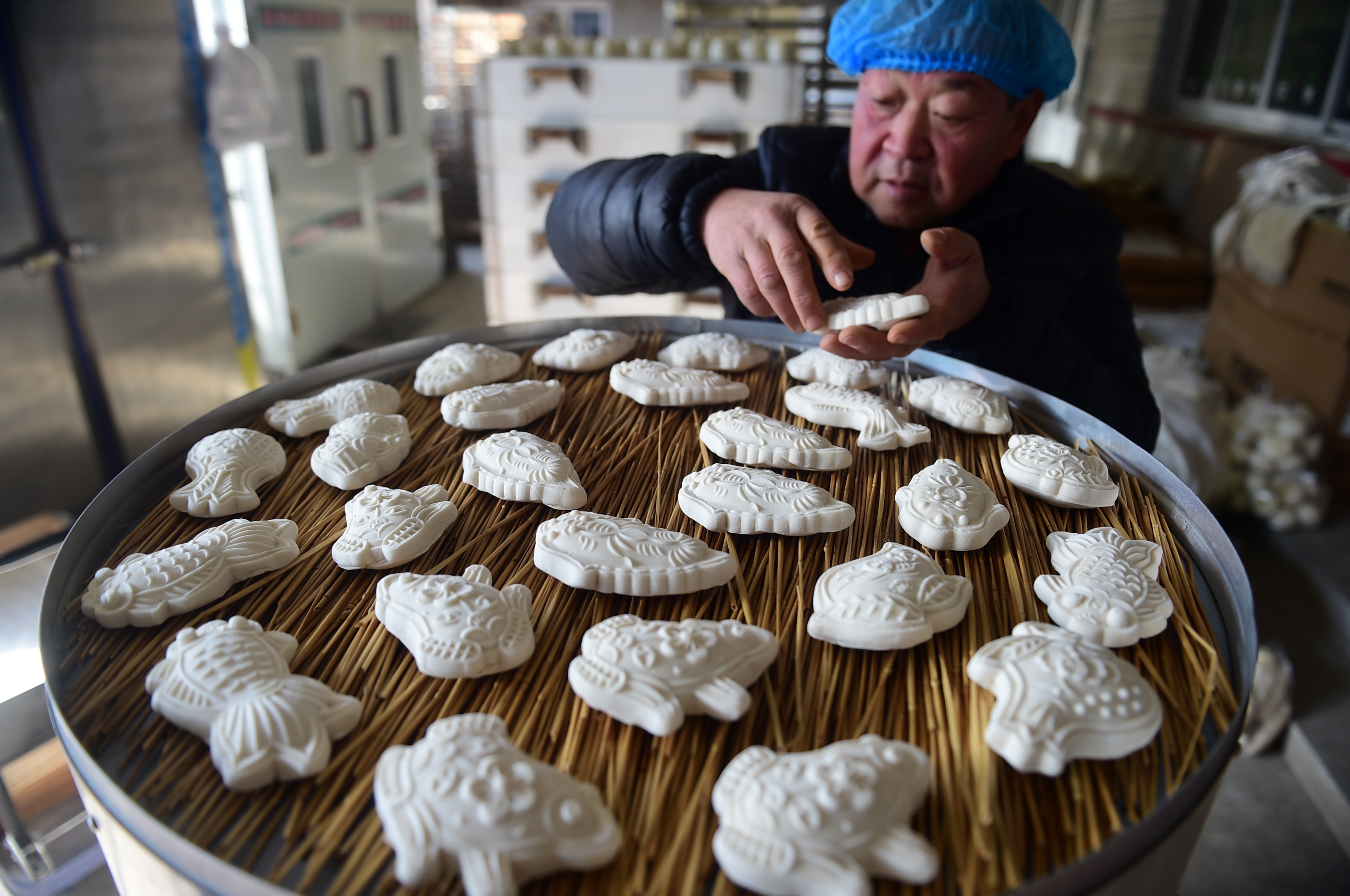 1月22日，滄州市海興縣張常豐村一家面花作坊的工人進行裝鍋作業。傅新春攝