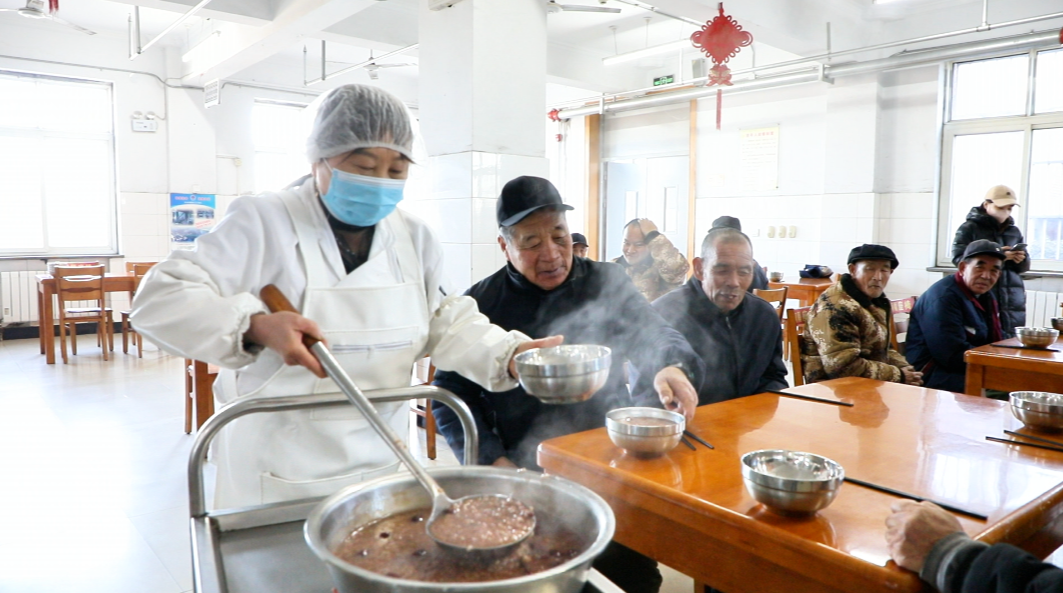 在迁安市第三福利院，老人在一起品尝腊八粥。王志斌摄