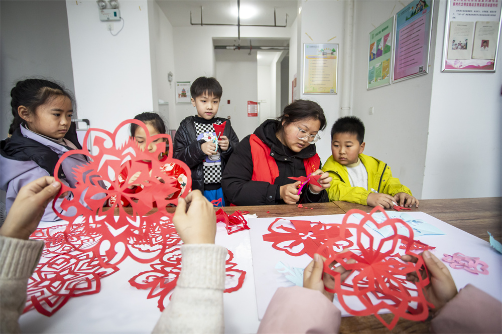 1月29日，河北省邯郸市复兴区胜利桥街道复兴路社区，“返家乡”大学生志愿者指导孩子们学习剪纸艺术。聂长青摄