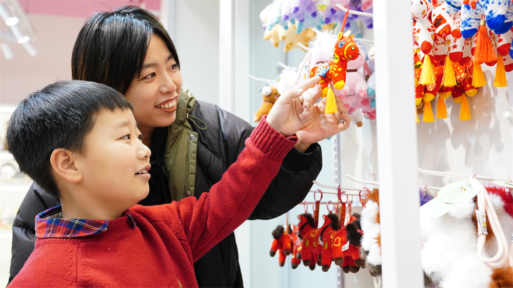 1月30日，白沟新城毛绒玩具BGT产业园一家毛绒玩具店内，顾客带孩子选购马元素挂件。孙浩龙摄