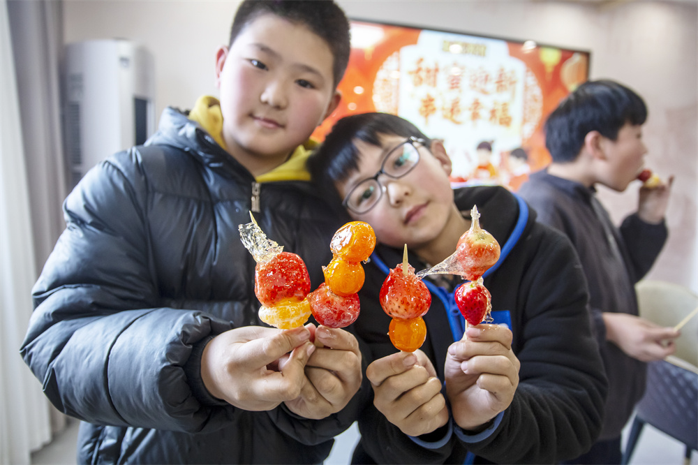 2月3日,河北省邯鄲市復興區二六七二街道東高河村,孩子們在品嘗自己動手制作的糖葫蘆。聶長青攝