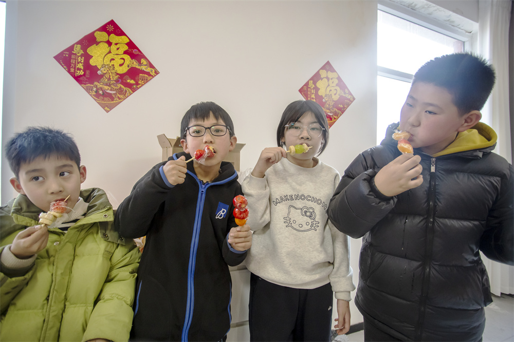 2月3日，河北省邯鄲市復興區二六七二街道東高河村，孩子們在品嘗自己動手制作的糖葫蘆。聶長青攝