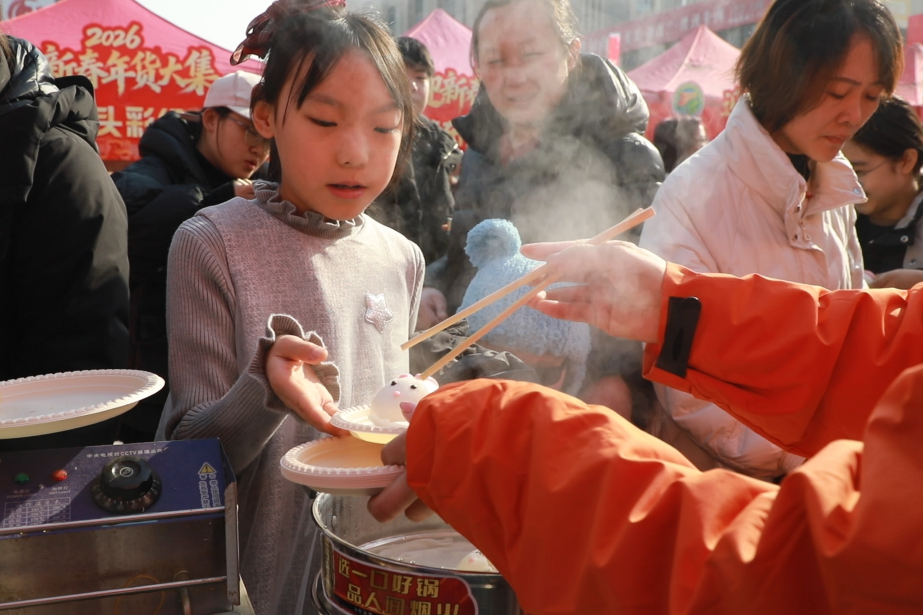 2026年2月4日，热气腾腾的年味美食吸引小朋友驻足品尝，现场洋溢着浓浓的节日氛围。马凯摄