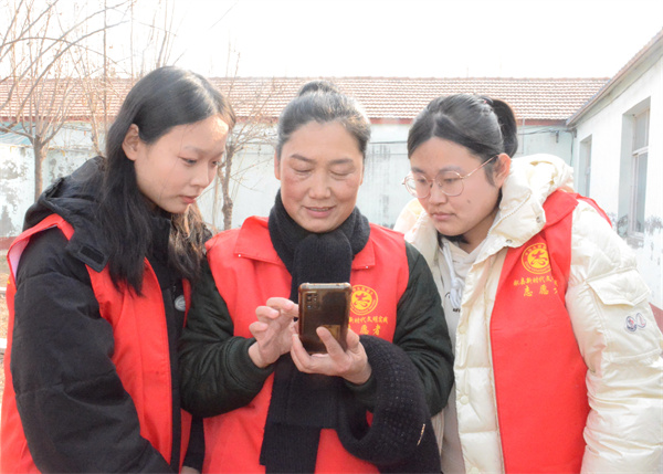 李俊英正在向返鄉大學生展示事跡照片。胡宇婷攝