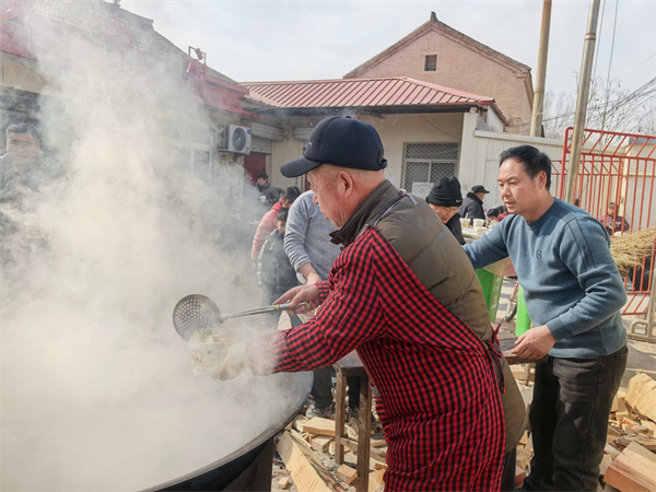 鸡泽县曹庄镇史邱寨村小年团圆饭现场，村里志愿者正在给老人盛水饺。吴军山摄