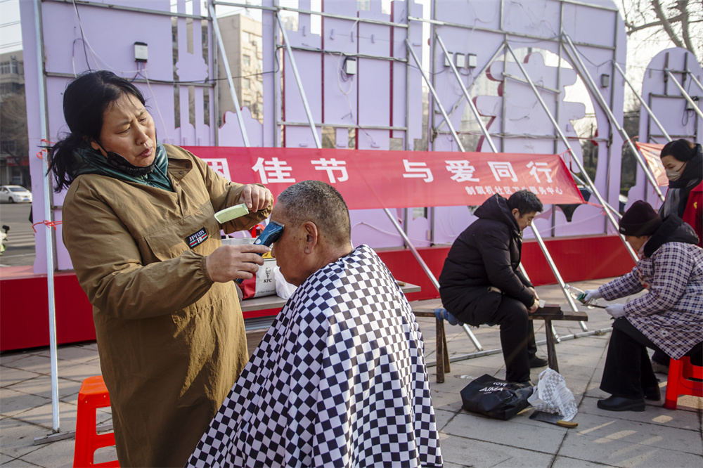在便民服务区，志愿者为居民免费提供理发、磨剪子、戗菜刀服务。聂长青摄
