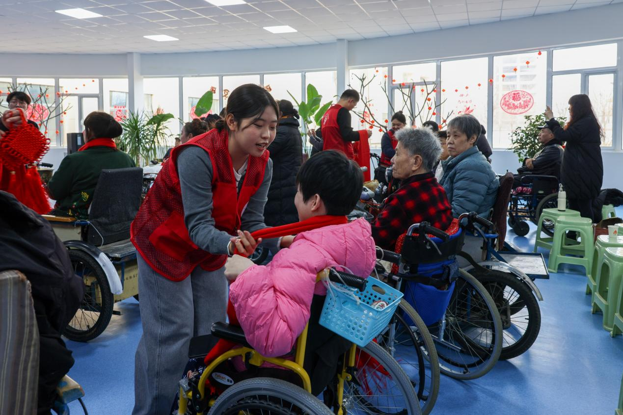 志愿者为截瘫休养员佩戴红围巾。马佳明摄